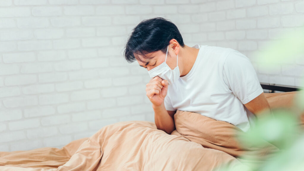 ベッドで咳をする男性